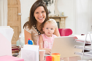 Mother with child on her lap at her work desk with her laptop open. = https://www.quincymutual.com/index.htm